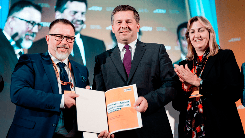 Drei Personen halten das Regierungsprogramm in den Händen (Generalsekretär Mario Karschunke, Ministerpräsident Sven Schulze, Europaabgeordnete Alexandra Mehnert)